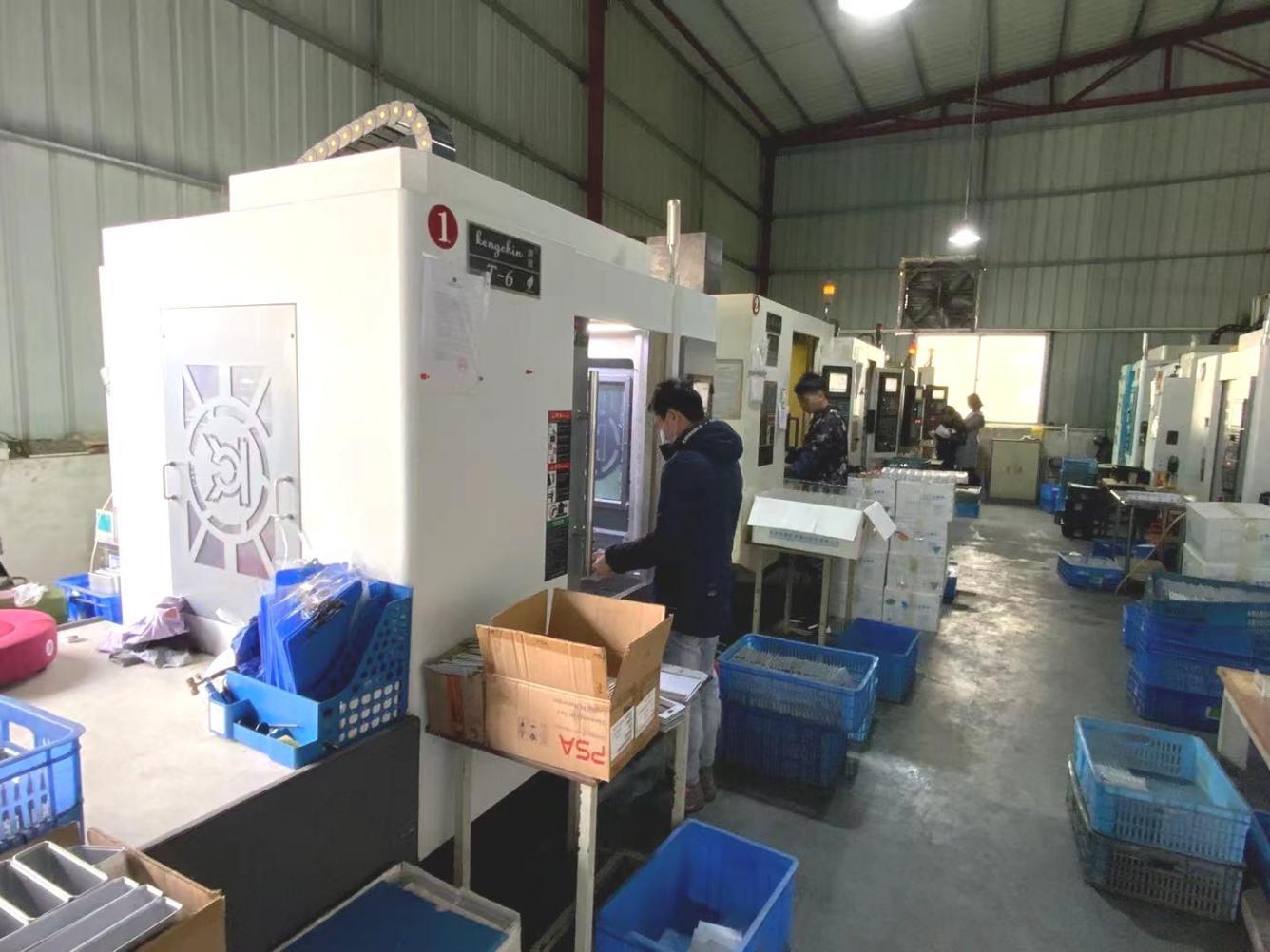 Staff working at enclosed machining centres in the workshop.